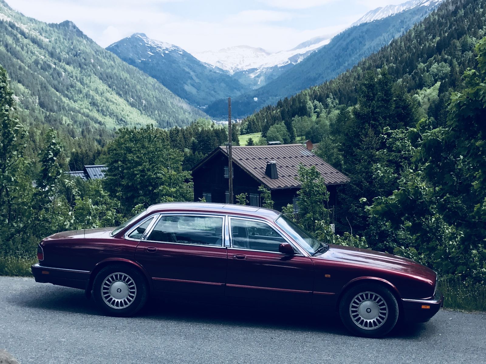A maroon Jaguar XJ saloon on a mountain road